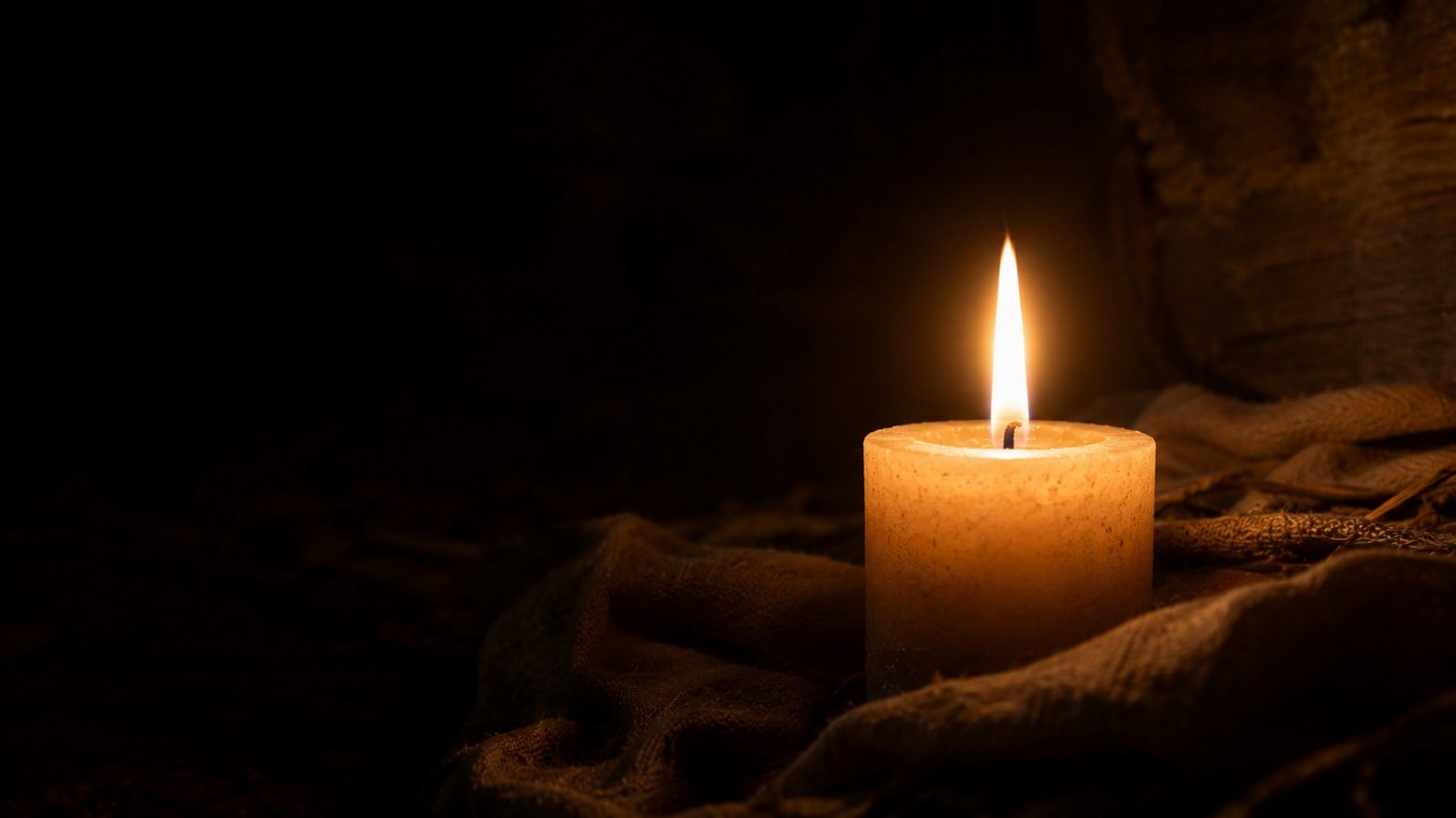 A single candle glowing warmly in darkness